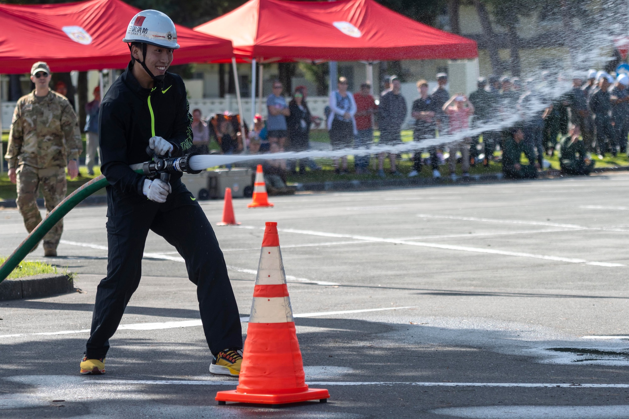 A firefighter with the Misawa City Fire Department sprays a fire hose during the annual Fire Prevention Week Fire Muster competition at Misawa Air Base, Japan, Oct. 12, 2023.