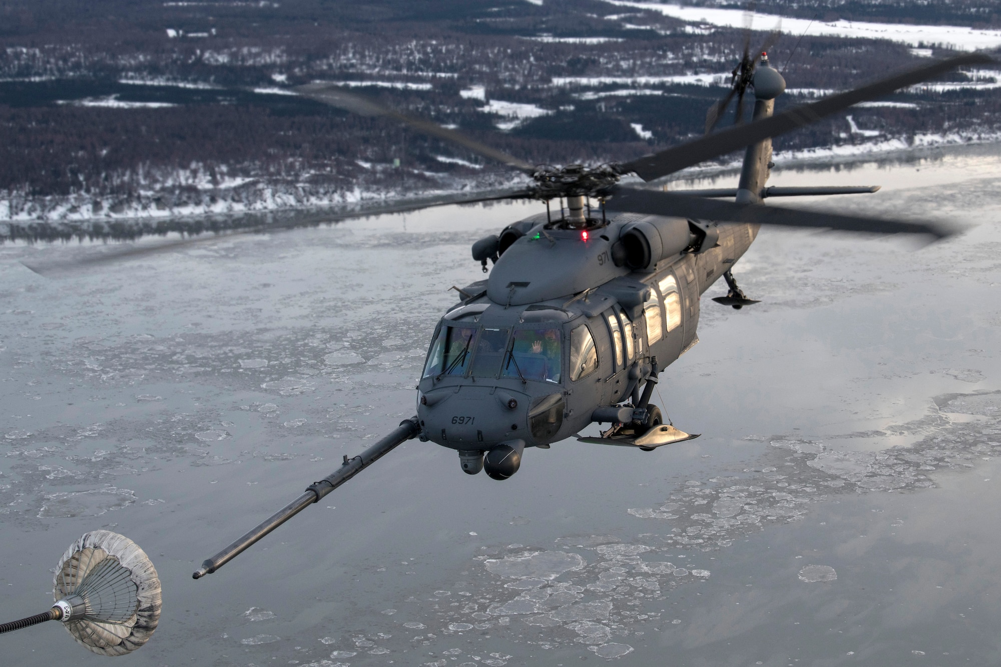 A U.S. Air Force HH-60G Pave Hawk helicopter assigned to the 210th Rescue Squadron, Alaska Air National Guard, conducts aerial refueling from a U.S. Air Force HC-130J Combat King II assigned to the 211th Rescue Squadron, Alaska Air National Guard, over Alaska, Jan. 21, 2021, during Operation Noble Defender.