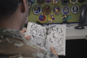 a man in a military uniform reads a comic book while sitting at a desk