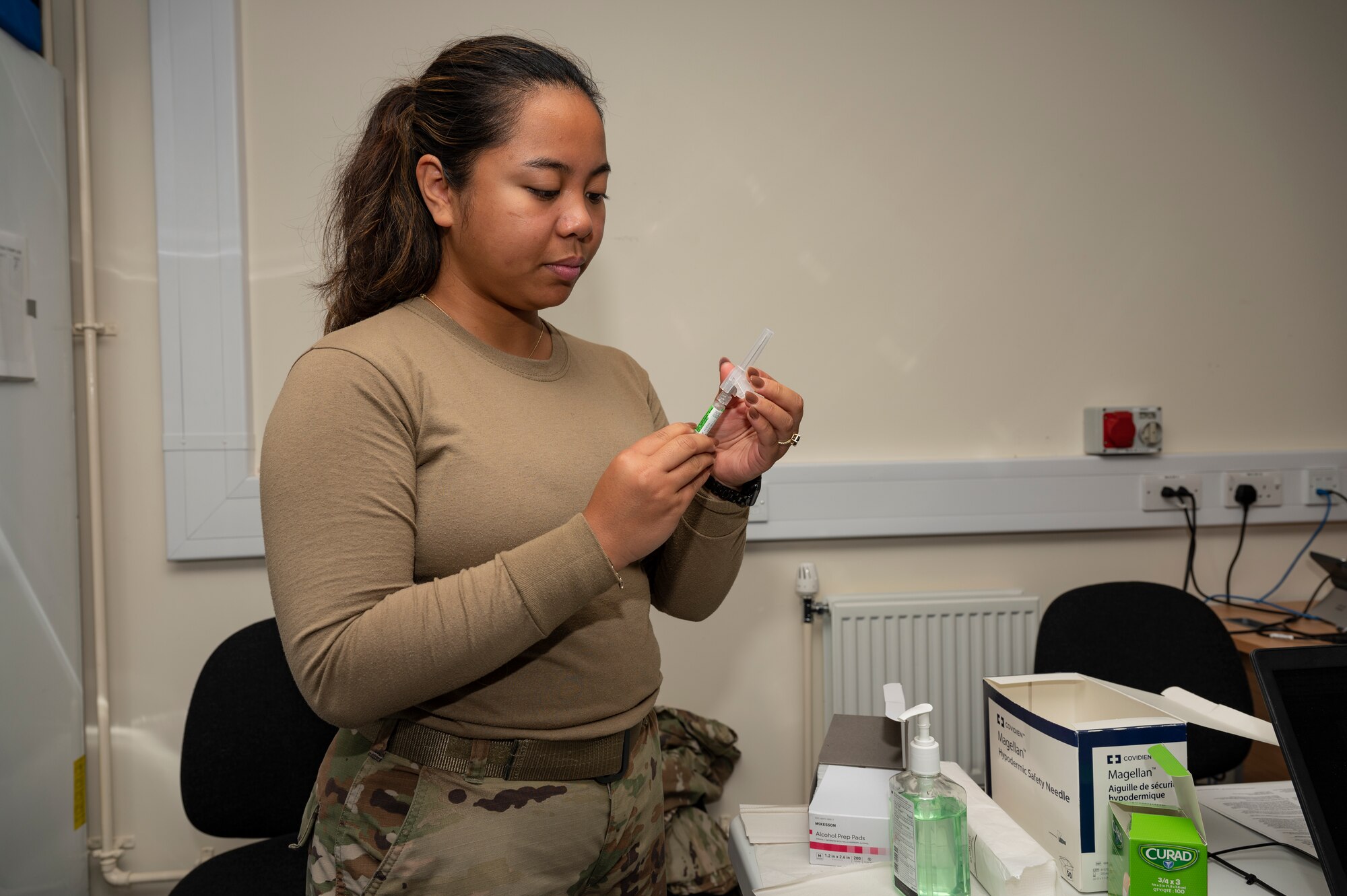 Staff Sgt. Noreen Arias, 9th Expeditionary Bomb Squadron independent duty medical technician, prepares a flu shot at RAF Fairford, United Kingdom, Oct. 19, 2023. Ensuring the 9th EBS Airmen are up to date on their immunizations helps avoid preventable diseases and maintains the squadron's mission readiness to respond to and support global operations. (U.S. Air Force Photo by Senior Airman Ryan Hayman)