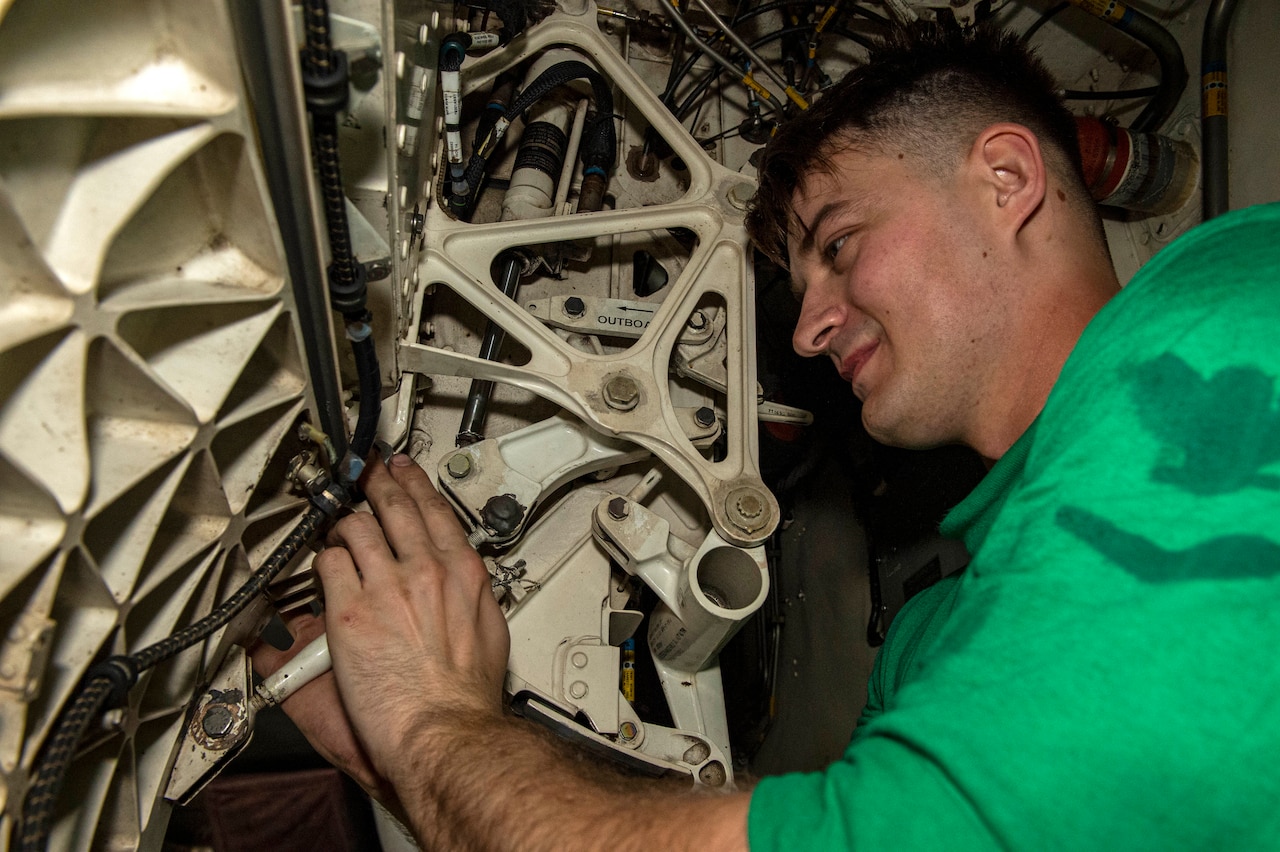 Sailor works on piece of gear.