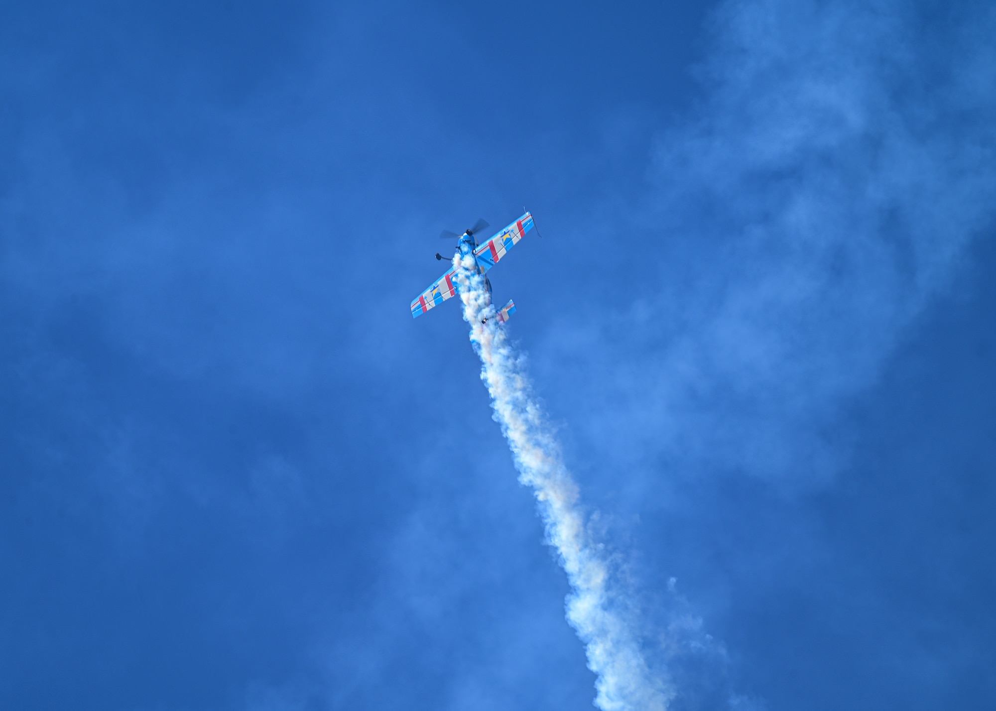 A stunt plane flies upward into the sky.