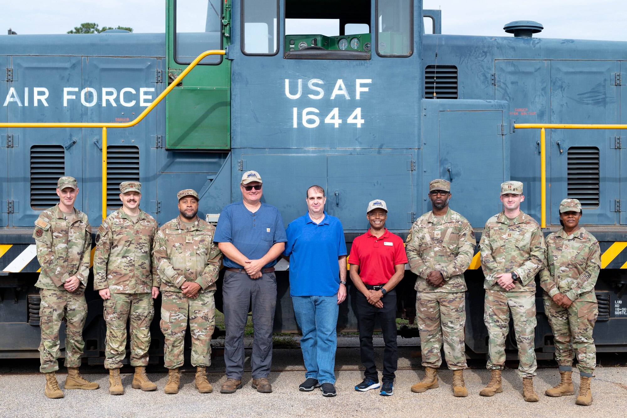 A group of people assigned to the 20th Fighter Wing pose in front of a train.