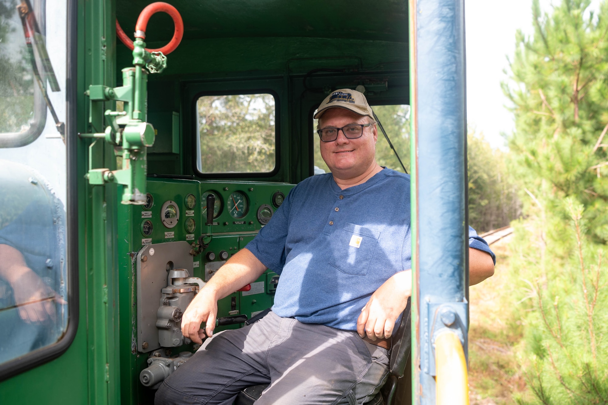 Man posing in locomotive driver seat.