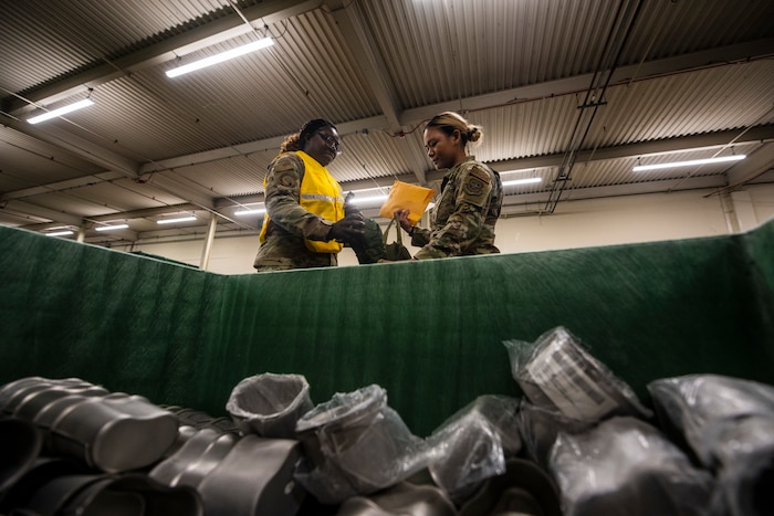 two women are seen behind a large storage container filled with cups.