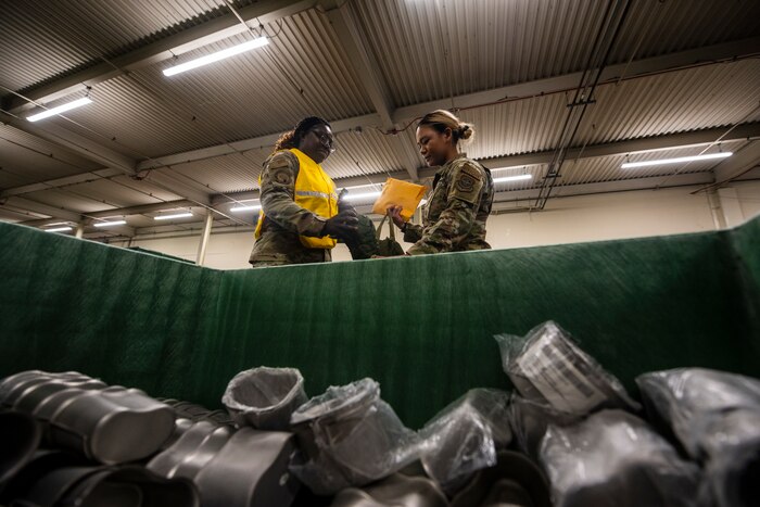 two women are seen behind a large storage container filled with cups.