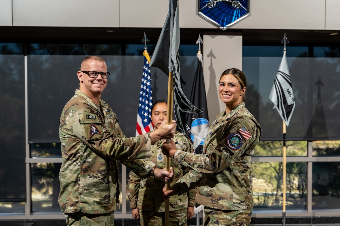 Two military members pass a guidon