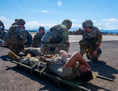 Airmen prepare to lift a simulated patient into a medical transport vehicle