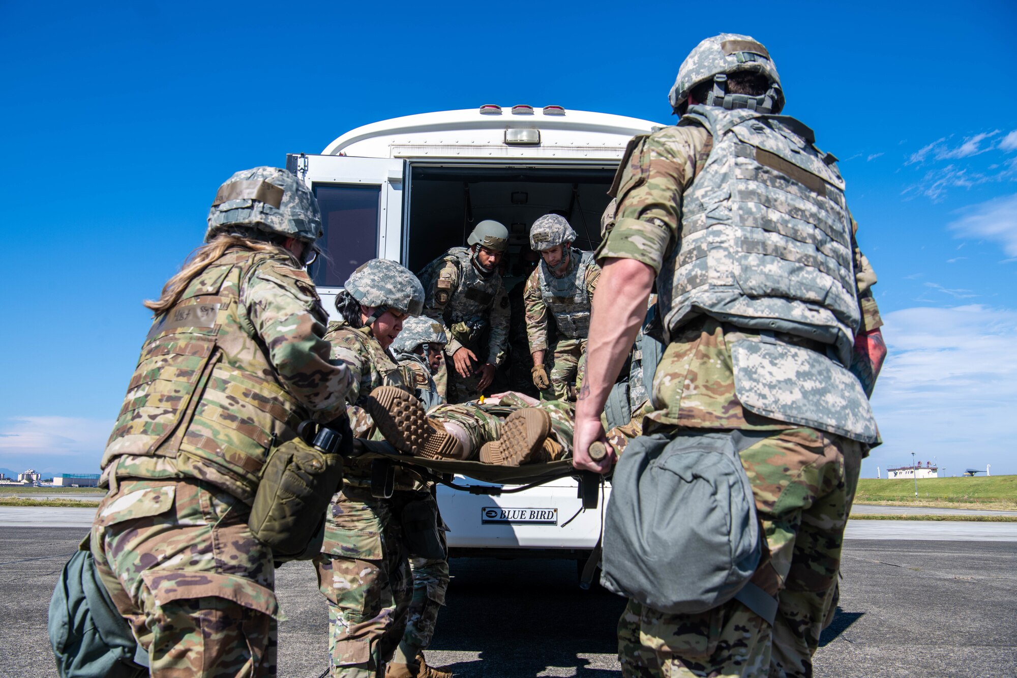 Airmen lift a simulated patient into a medical transport vehicle