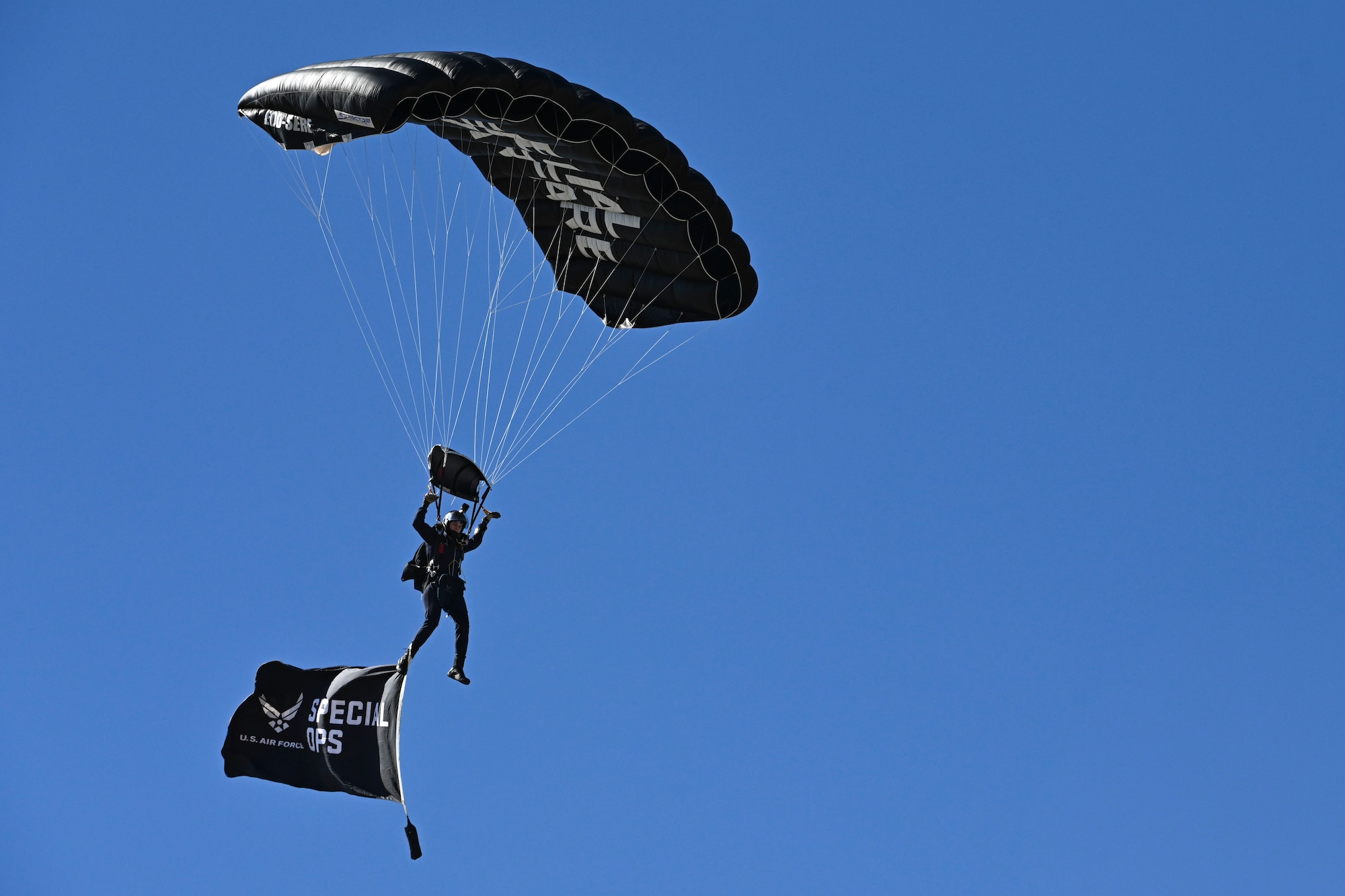 Paratroopers flying in air with unit flag.