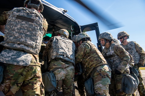 Airmen from the 374th Medical Group work together to remove a simulated patient from a helicopter