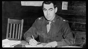 First DLA Director McNamara sits at a desk with pencil in hand signing paperwork.
