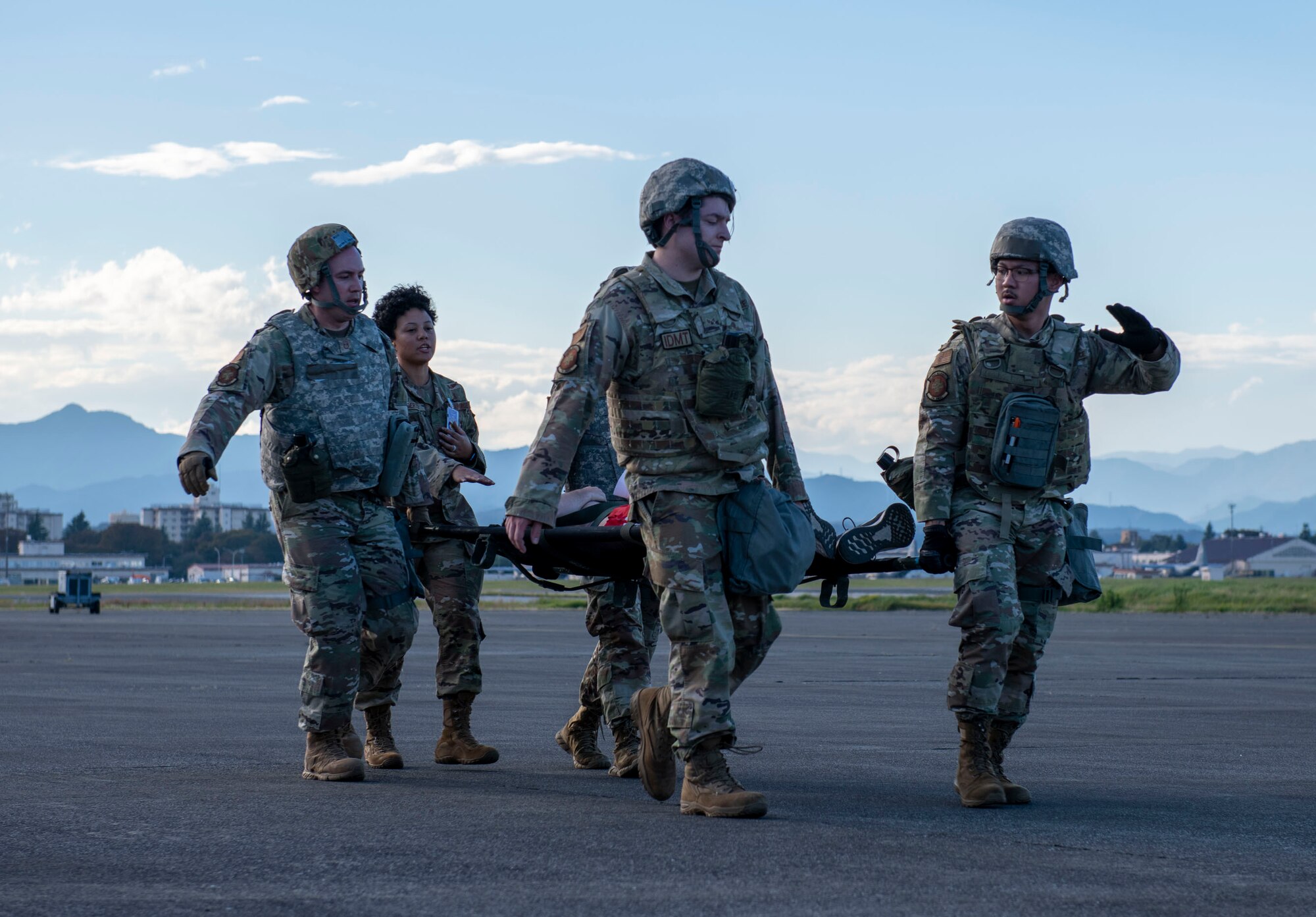 Airmen carry a simulated patient from an aircraft to a medical transport vehicle