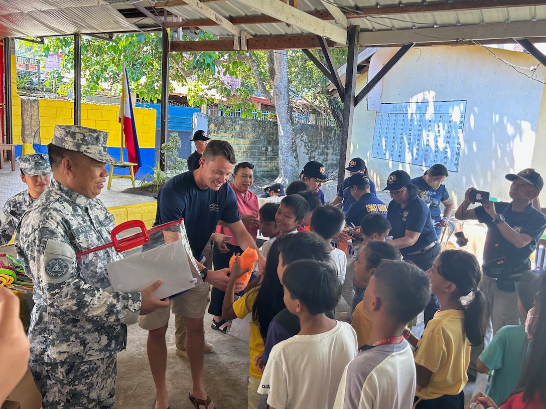 Lt. Patrick Dreiss, commanding officer of USCGC Frederick Hatch (WPC 1143), and colleagues from the Philippine Coast Guard greet children at Bliss Elementary School in Tacloban, Philippines, on Oct. 21, 2023. In a historic first, the USCGC Frederick Hatch (WPC 1143) visited Tacloban, Philippines, from Oct. 19 to 23, 2023, and the crew conducted engagements marking a significant milestone in the enduring relationship between the United States and the Philippines. (U.S. Coast Guard photo by Lt. Anna Vaccaro)