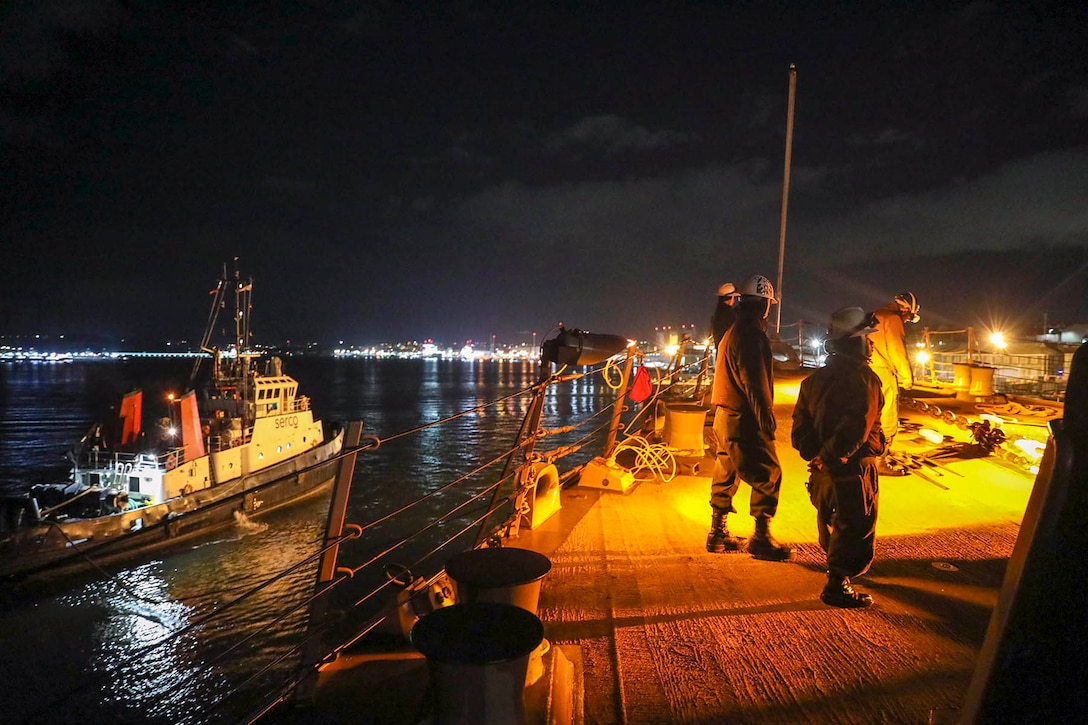Sailors make preparations to get underway at twilight.