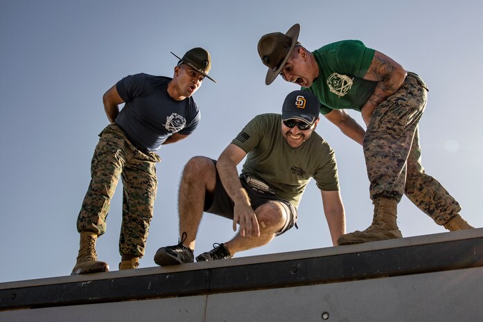 U.S. Marine Corps drill instructors with Marine Corps Recruit Depot San Diego motivate a participant of the Boot Camp Challenge as they navigate a wall, Oct. 21, 2023. For the past 21 years the Boot Camp Challenge has offered a unique opportunity to the public to step into the shoes of a future Marine, guided by drill instructors to conquer a three-mile obstacle race and gain experience into what recruits go through during boot camp. (U.S. Marine Corps photo by Sgt. Yvonna Guyette)