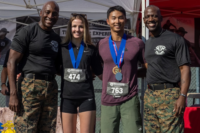 U.S. Marine Corps Commanding General Brig. Gen. James A. Ryans II, left, and Sgt. Maj. Oranjel Leavy, right, Marine Corps Recruit Depot San Diego and the Western Recruiting Region, pose with the 1st place male and female participants of the Boot Camp Challenge, at Marine Corps Recruit Depot San Diego, Oct. 21, 2023. For the past 21 years the Boot Camp Challenge has offered a unique opportunity to the public to step into the shoes of a future Marine, guided by drill instructors to conquer a three-mile obstacle race and gain experience into what recruits go through during boot camp. (U.S. Marine Corps photo by Cpl. Alexander O. Devereux)