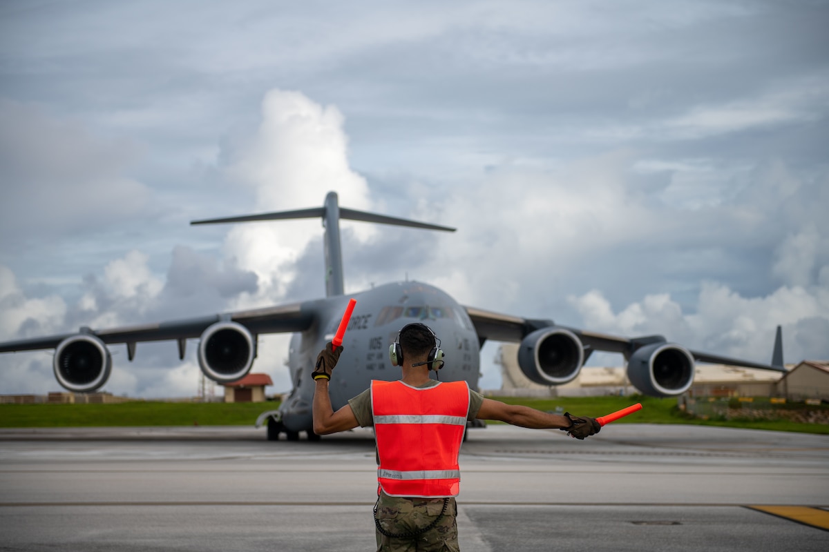 Airman 1st Class Kendall Reed from the 172nd Aircraft Maintenance Squadron, Jackson, Mississippi marshals a C-17 Globemaster III onto the runway during a two-week annual training tour on August 8, 2023, at Anderson Air Force Base, Guam. This training is a requirement for all guardsman and ensures they receive the necessary experience to be multi-capable Airmen. U.S. Air National Guard photo by Tech. Sgt. Vanessa Rivera.