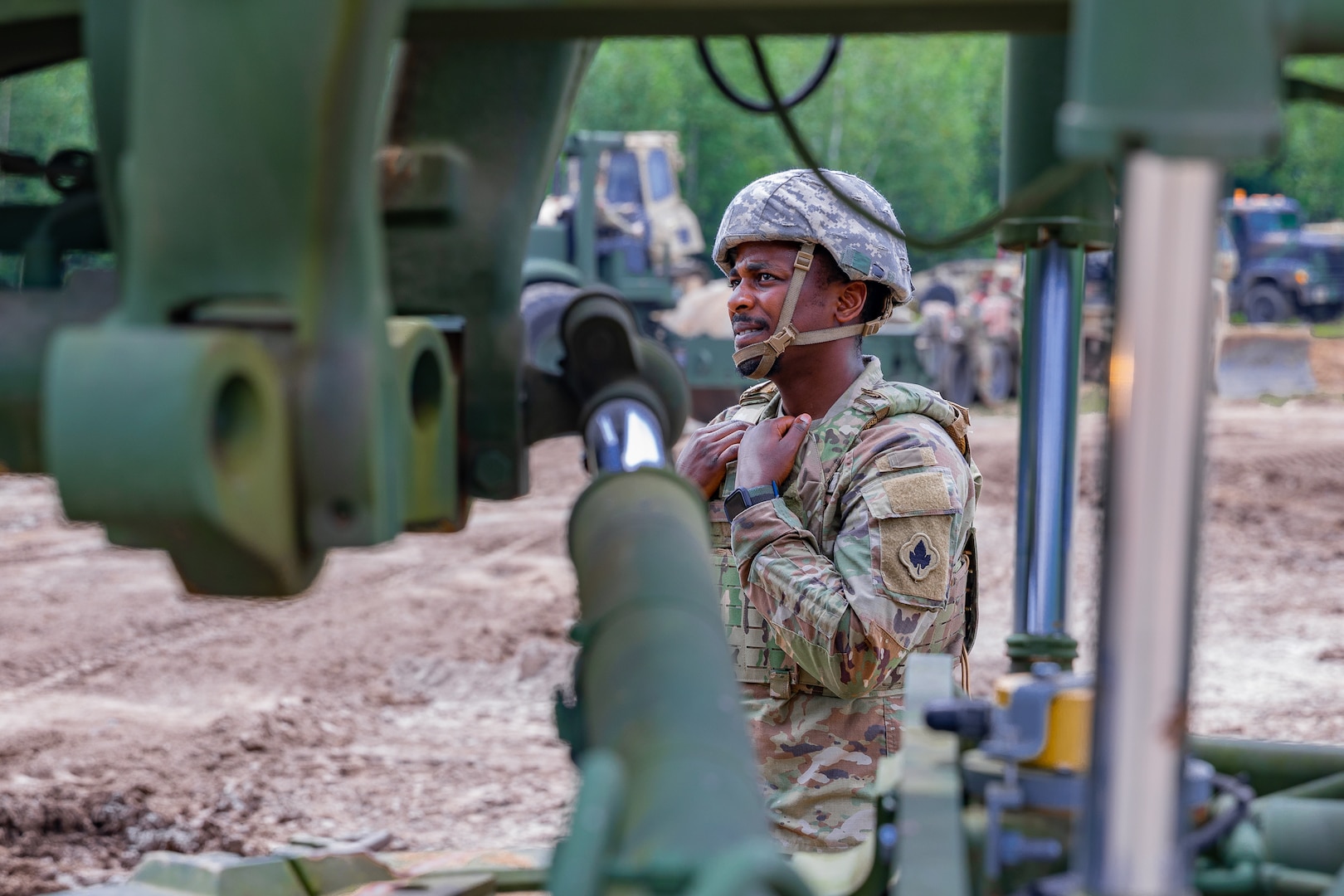 Connecticut Army National Guard Spc. Miracle Sam, a horizontal construction engineer assigned to the 248th Engineer Company, 192nd Engineer Battalion, looks up toward the cab of a grader operated by Spc. Ashano Folkes during annual training at Fort Drum, New York, Aug. 10, 2023.