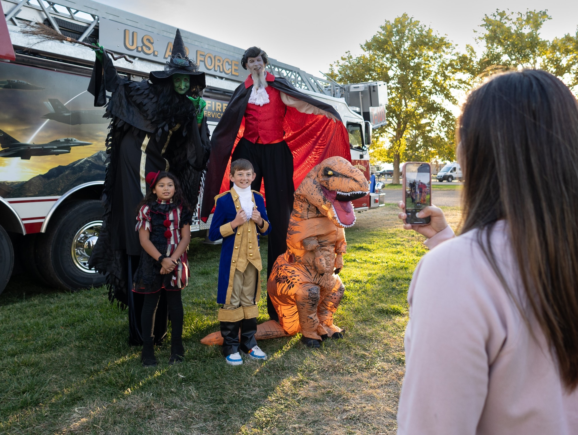 Kids in costume pose for a photo in front of a fire truck