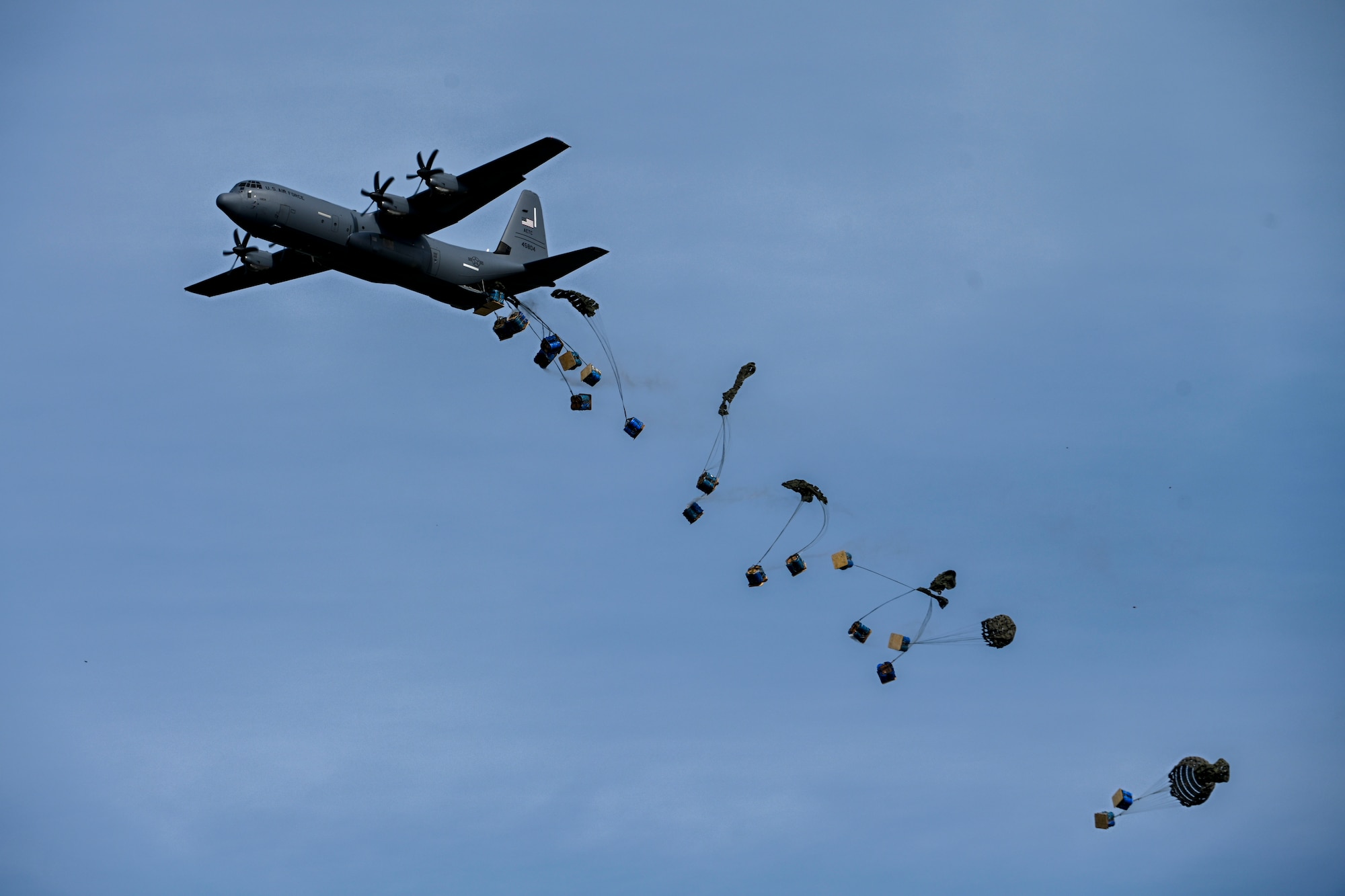 Paratroopers jump out of a C-130J Super Hercules.
