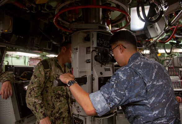 Cmdr. Ilbae Kim, commanding officer of ROKS Jeong Ji (SS 073), looks through a periscope aboard  USS Annapolis (SSN 760).