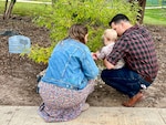 Family kneeling placing rocks under a tree