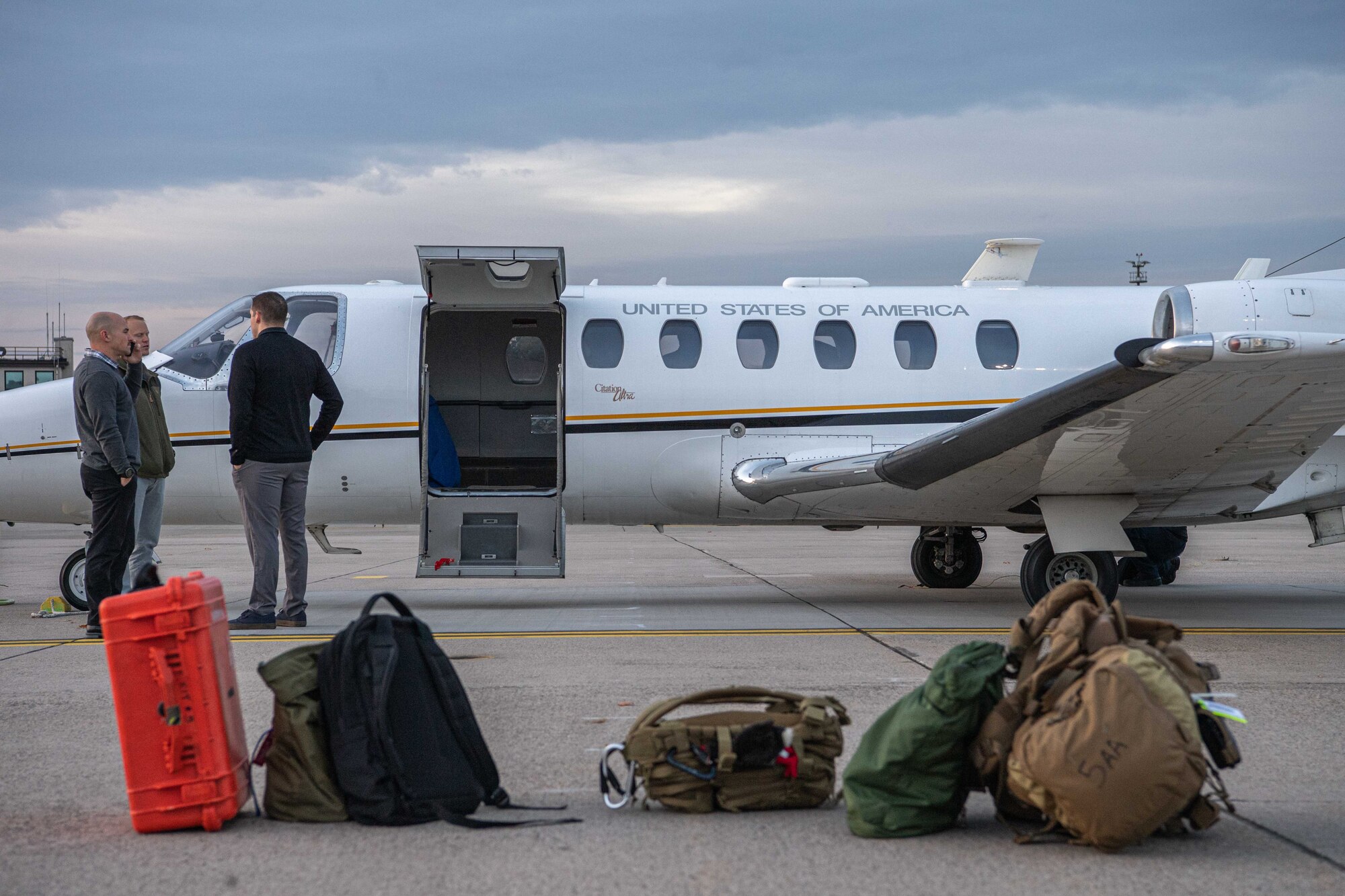 Gear lays on the ground while 3 men talk