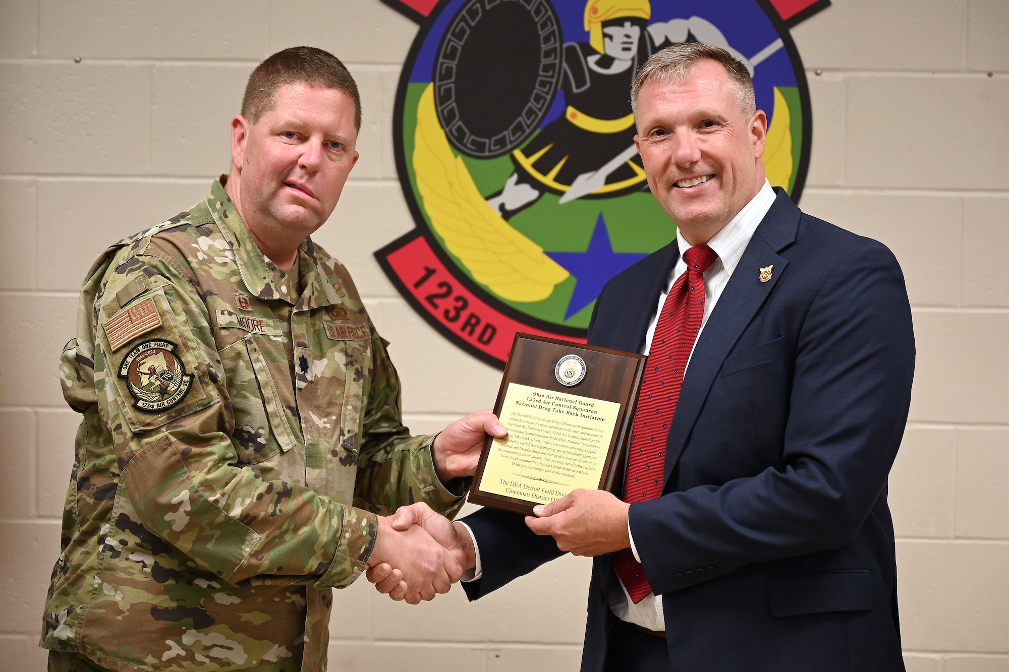 U.S. Air Force Col. Bryan Moore, commander of the 123rd Air Control Squadron, receives an award from Joseph Reader, the resident agent in charge of the Drug Enforcement Agency - Cincinnati district office, during a ceremony Sept. 13, 2023 in Blue Ash, Ohio. The award recognized the 123rd's contributions to the Cincinnati DEA's drug takeback program, which resulted in removing more than 800 pounds of prescription drugs from local communities. (U.S. Air National Guard photo by Shane Hughes)