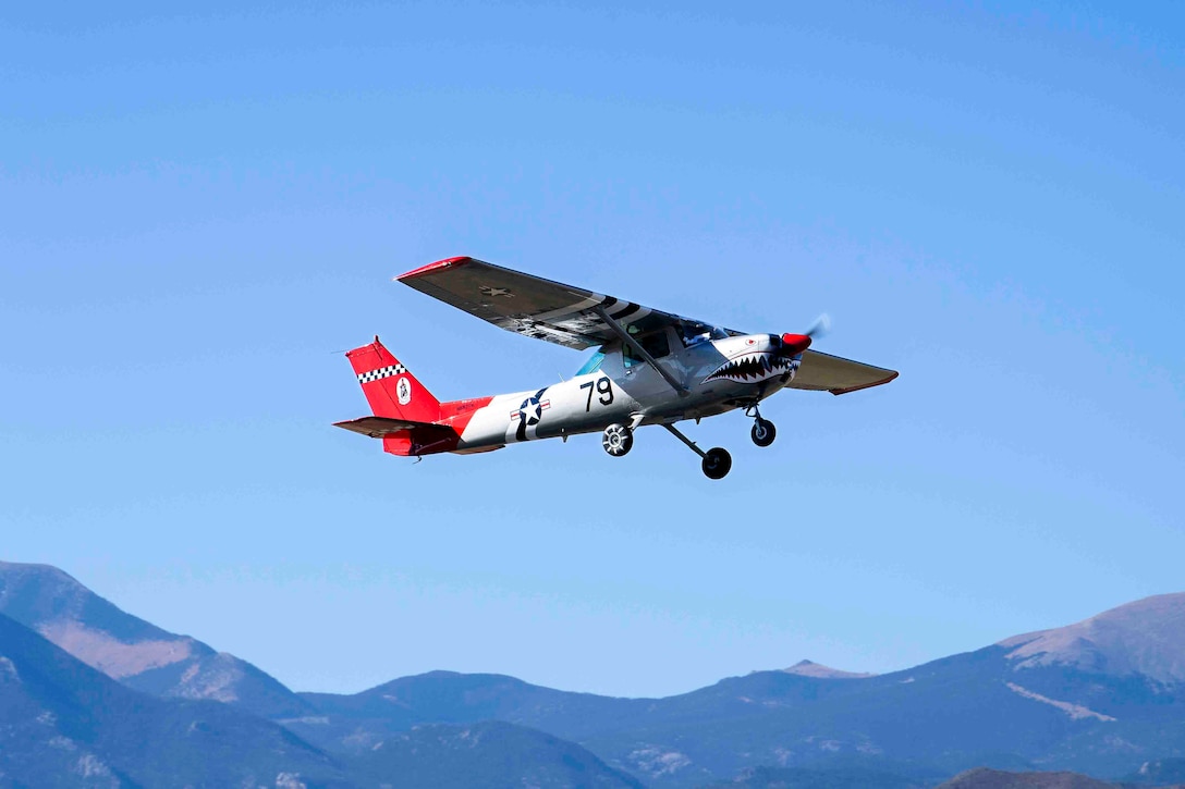 An aircraft flies with mountains in the background.