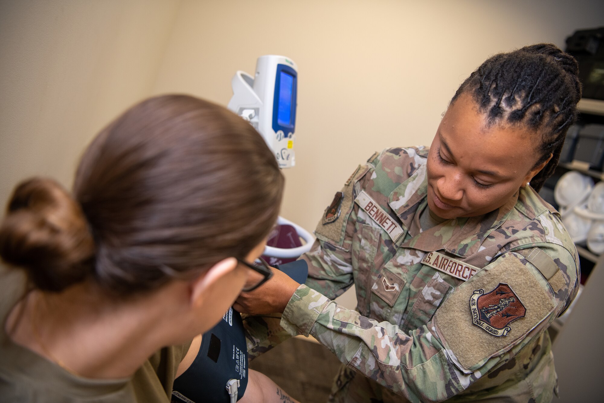 Airman applying blood pressure cuff to patient.