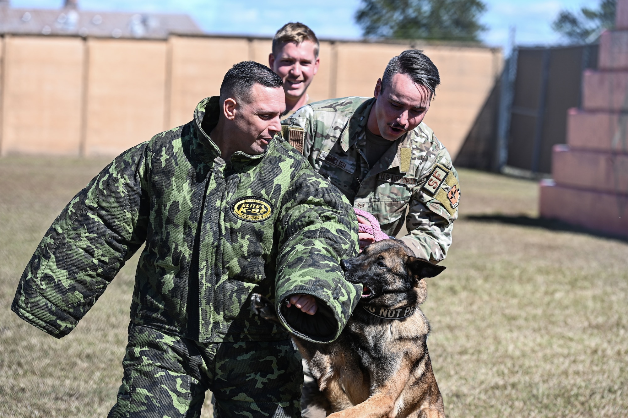 U.S. Air Force Col. Pedro Matos, 14th Mission Support Group commander runs from K-9 Dalton while handlers SrA Colin English and SSgt Devon Reynolds position themselves to be ready to assist at Columbus Air Force Base, MS, Oct. 16, 2023. Matos was still able to feel the strength of the bite through the safety suit. (U.S. Air Force photo by A1C Jessica Blocher)