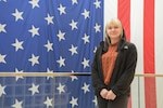 TRICARE liaison stands in front of American flag.
