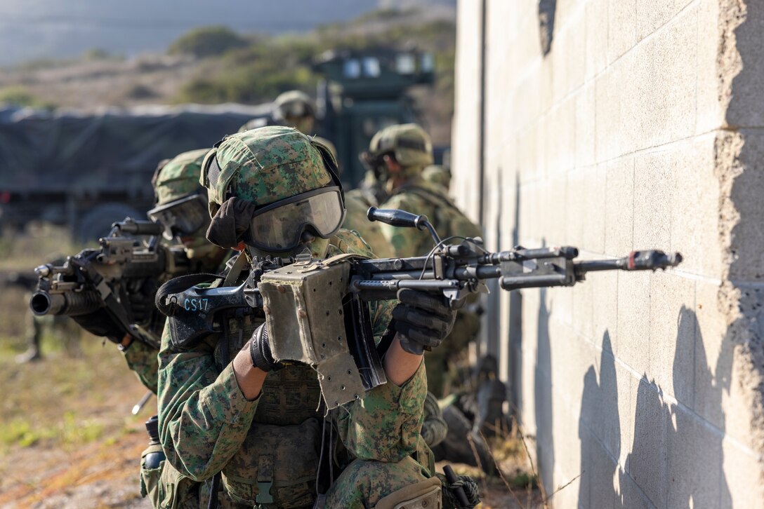 Singapore Guardsmen from 7th Singapore Infantry Brigade prepare to enter a building during an amphibious assault exercise, as part of Exercise Valiant Mark 2023 at Camp Pendleton, CA, Oct. 18, 2023. Valiant Mark 23 is an annual, bilateral training exercise conducted between the Singapore Armed Forces and I Marine Expeditionary Force, designed to enhance interoperability, improve combined arms and amphibious warfighting skills, and strengthen military-to-military relationships. (U.S. Marine Corps photo by Sgt. Nicolas Atehortua)