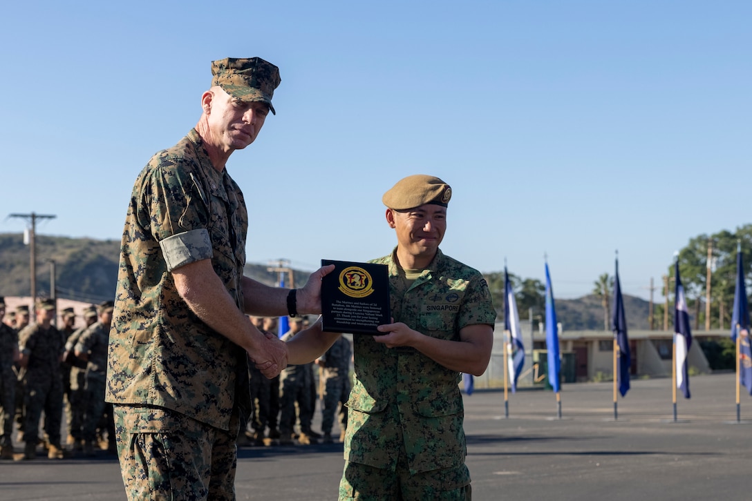 U.S. Marine Corps Lt. Col. Patrick Holland, left, commanding officer,2nd Battalion, 4th Marines and Singapore Armed Forces Lt. Col. Stanley Lim, commanding officer, 7th Singapore Infantry Brigade, exchange gifts during the closing ceremony for Exercise Valiant Mark 2023 at Camp Pendleton, CA, Oct. 20, 2023. Valiant Mark 23 is an annual, bilateral training exercise conducted between the Singapore Armed Forces and I Marine Expeditionary Force, designed to enhance interoperability, improve combined arms and amphibious warfighting skills, and strengthen military-to-military relationships. (U.S. Marine Corps photo by Sgt. Nicolas Atehortua)