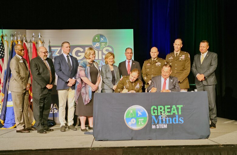 Maj. Gen. Kimberly Colloton (left),  and Juan Rivera, chairman of the board for GMIS signs the agreement as other senior leaders from both the Corps and GMIS  observe.