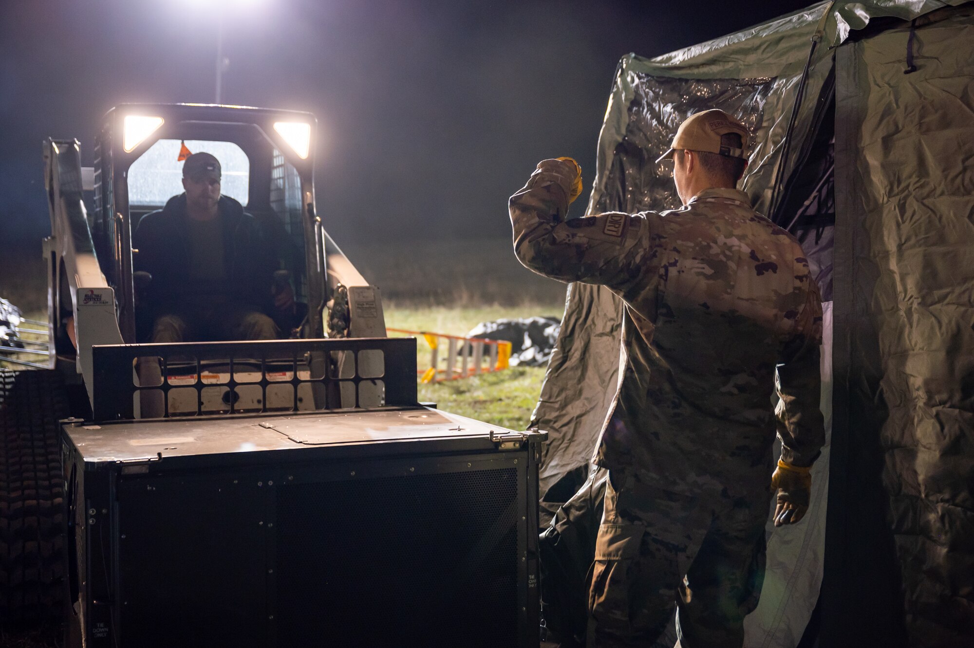 Senior Airman Diego Perez Herrera, 341st Civil Engineer Squadron, pavements and construction equipment journeyman, instructs a heavy machine operator on where to place a generator during Grizzly Rampart, a training exercise in Lewistown, Montana, Oct. 19, 2023. Participation in an exercise like Grizzly Rampart allows key agencies the ability to test response efforts ensuring proper and effective response with local and state first responders during times of crisis. (U.S. Air Force photo by Senior Airman Mary Bowers)