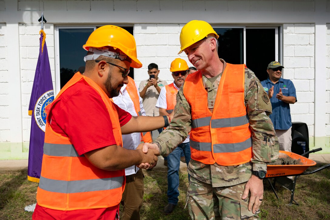 Honduras Minister of Education, Professor Daniel Esponda, left, and U.S. Maj. Gen. Evan Pettus, 12th Air Force (Air Forces Southern) commander, right, shake hands after a bricklaying ceremony at the System of Technological and Agricultural Innovation (SCITA) in Comayagua, Honduras, Aug. 4, 2023. U.S. Southern Command's Humanitarian Assistance Program donated $25,000 to SCITA for improvements to infrastructure that are key to ensuring quality education for Hondurans. (U.S. Air Force photo by Tech. Sgt. Rachel Maxwell)