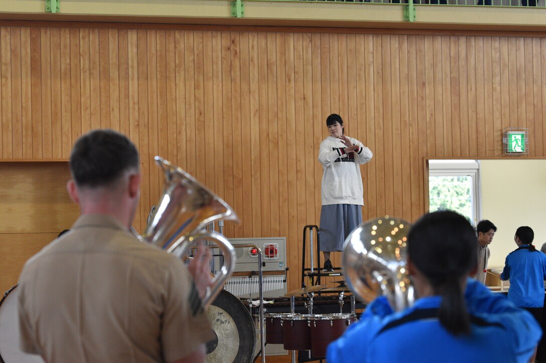 Asuka Furusawa, the Gotemba Nishi Junior High School band teacher leads a mixed group of Third Marine Expeditionary Force (III MEF) band members and students, October 14, 2023. The band members practiced together and Marines coached students, before a group performance. The III MEF Band was originally scheduled to perform at the 2023 Combined Arms Training Center, Camp Fuji Friendship Festival. (U.S. Marine Corps photo by Song Jordan)