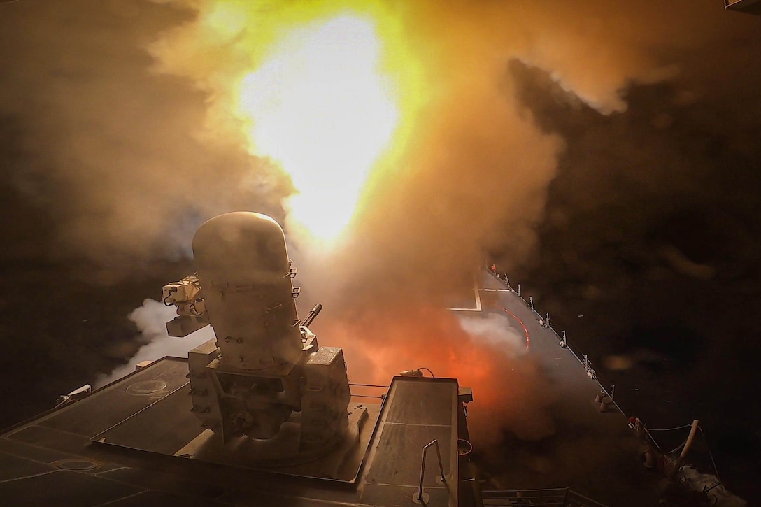 A military ship fires a missile sending flames into the air.