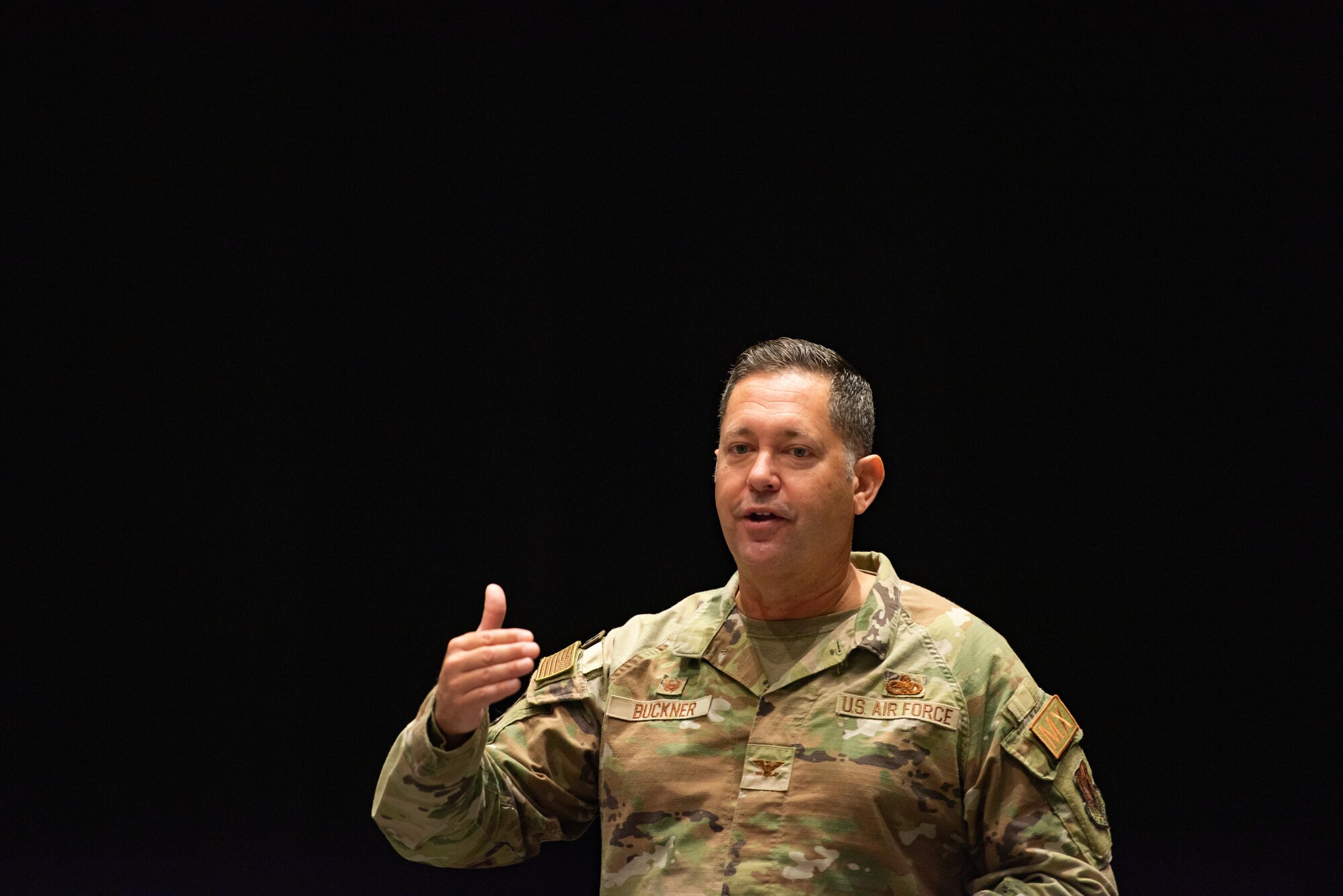 An Airmen stands in front of a crowd of student athletes in an auditorium