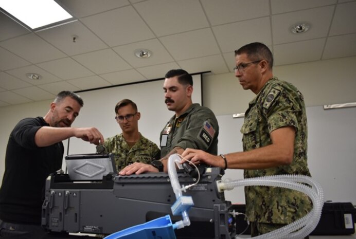 From left, a manufacture representative provides familiarization training of a mobile, integrated intensive care unit equipment with Lt. Kyle Rowland, a critical care nurse assigned to Navy Medicine Readiness and Training Command (NMRTC) Camp Lejeune, and Hospital Corpsman 2nd Class Bradley Christian, a search and rescue technician assigned to NMRTC Patuxent River, as Cmdr. David Goodrich, the lead research and development of naval expeditionary medical platforms assigned to U.S. Navy Bureau of Medicine and Surgery, observes at Naval Medical Readiness Logistics Command. Rowland and Christian are a part of a 2-person team with the En-Route Care System (ERCS), one of the Navy’s newest medical capabilities that will deploy for the first time with the Eisenhower Carrier Strike Group in order to meet the demands of maritime operations in a distributed environment. (U.S. Navy photo by Julius L. Evans) This photo has been altered for security purposes by blurring out access badges