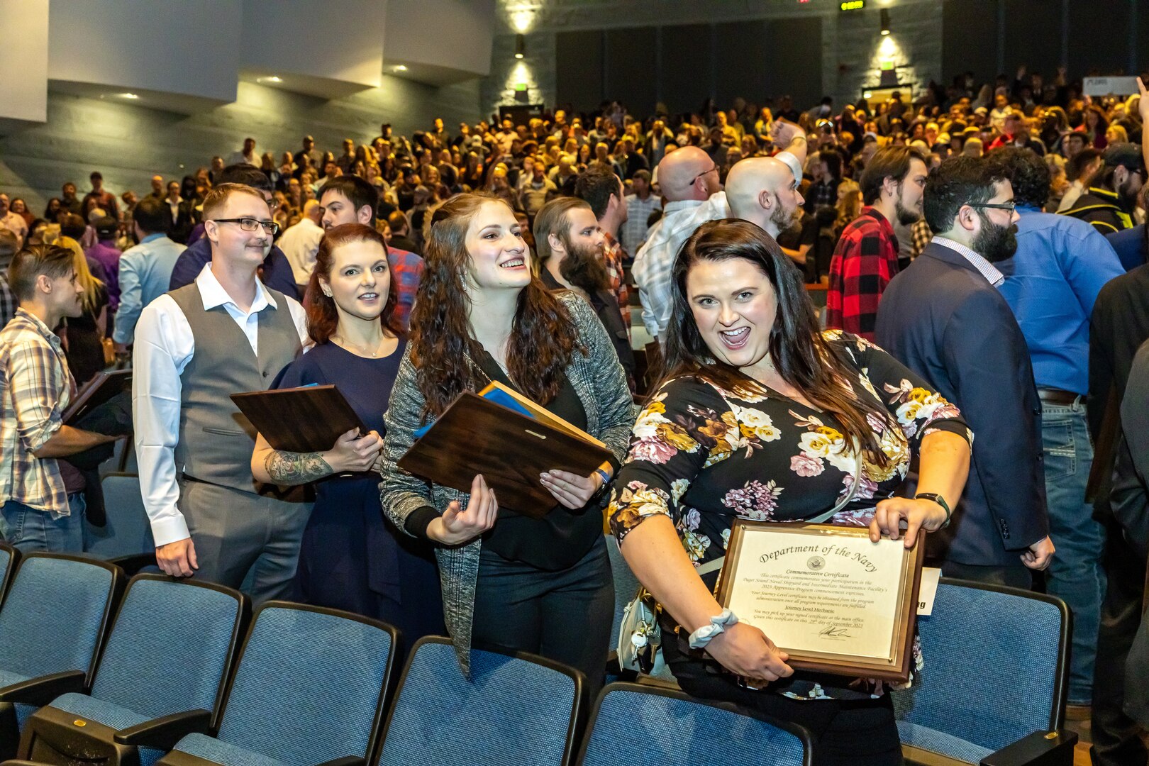 : Shop 26, Welders, apprentice class members (from left) Tyler Reynolds, Millie Stivers, Caitlin Sutter and Monika Westerfield celebrate as they exit the auditorium following the annual Puget Sound Naval Shipyard & Intermediate Maintenance Facility Apprentice Program graduation ceremony Sept. 29, 2023, at the Bremerton High School Performing Arts Center, in Bremerton, Washington.  (U.S. Navy photo by Jeb Fach)