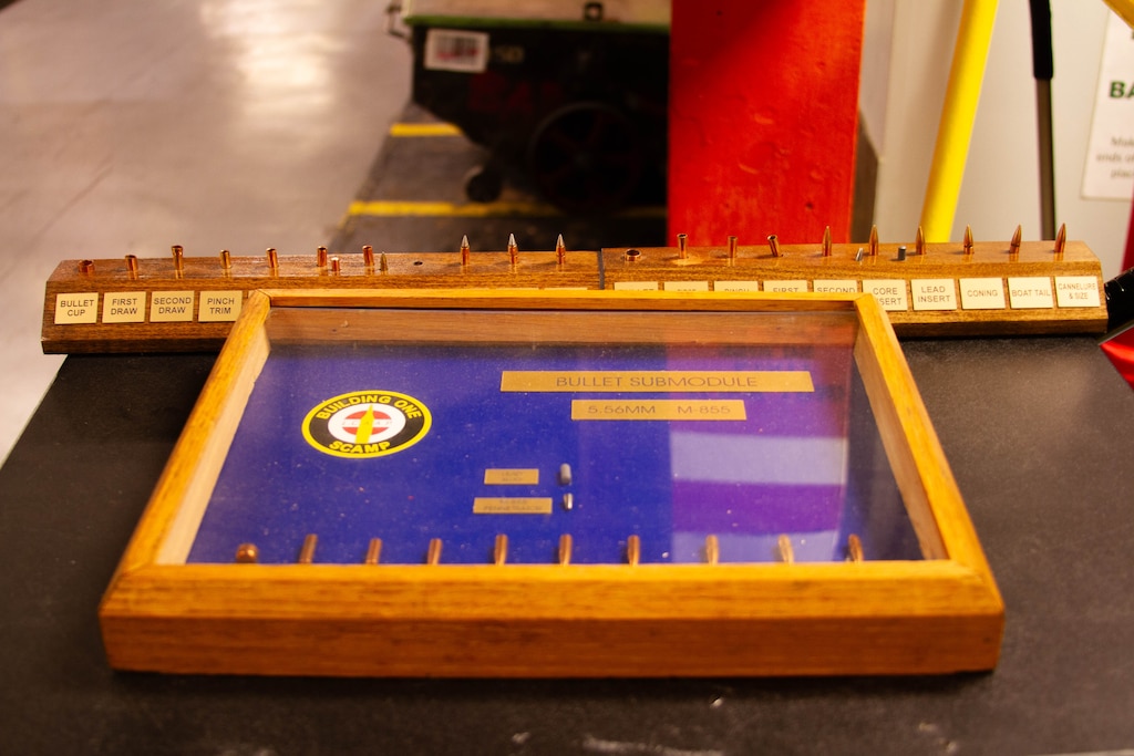 A glass display case holds ammunition with a blue background.