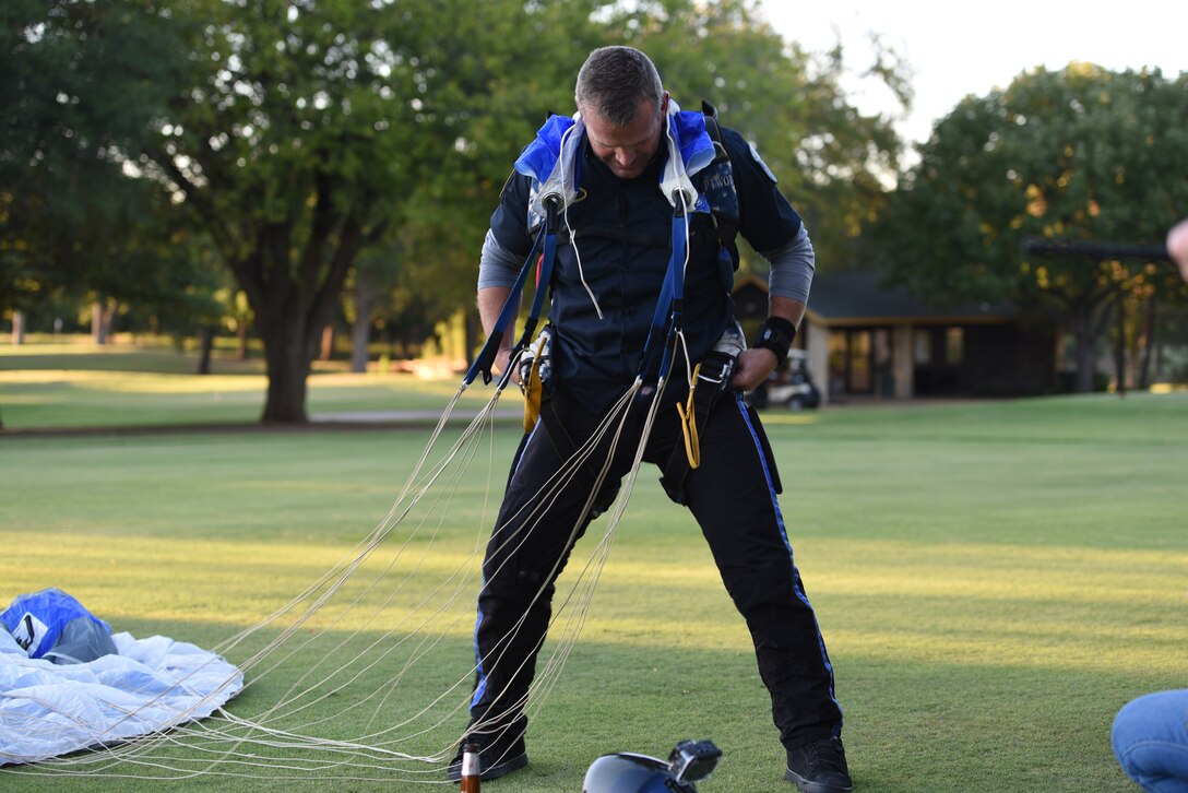 Major Paul Yeagley removes his harness after successfully landing his 2097th skydive in a field.