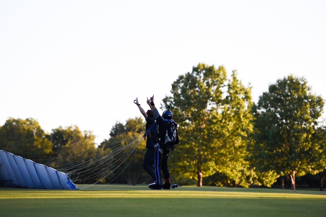 A man meets another man on a field to celebrate his successful sky dive.