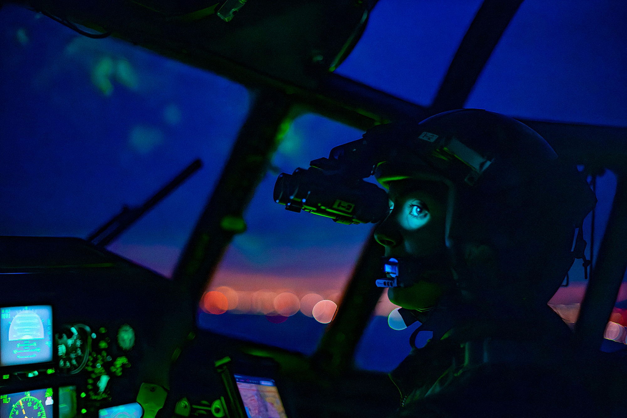 Pilot operating aircraft during dusk while wearing a helmet with Night Vision Goggles attached.