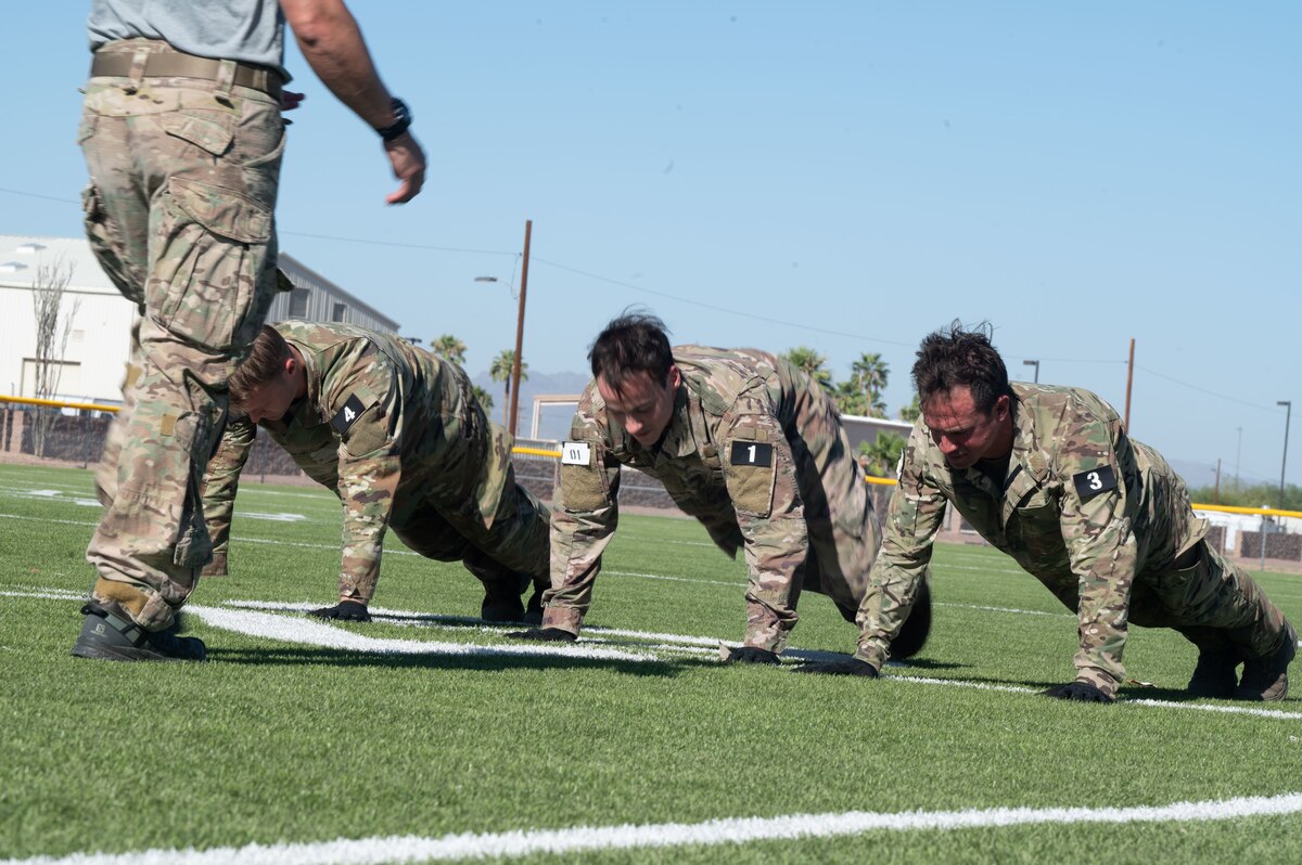 Candidates participating in a Combat Rescue Officer Phase II training exercise do pushups as a cadre evaluates them at Davis-Monthan Air Force Base, Ariz., Oct. 16, 2023. The physical fitness of candidates was assessed consistently during CRO Phase training. (U.S. Air Force photo by Airman 1st Class Robert Allen Cooke III)