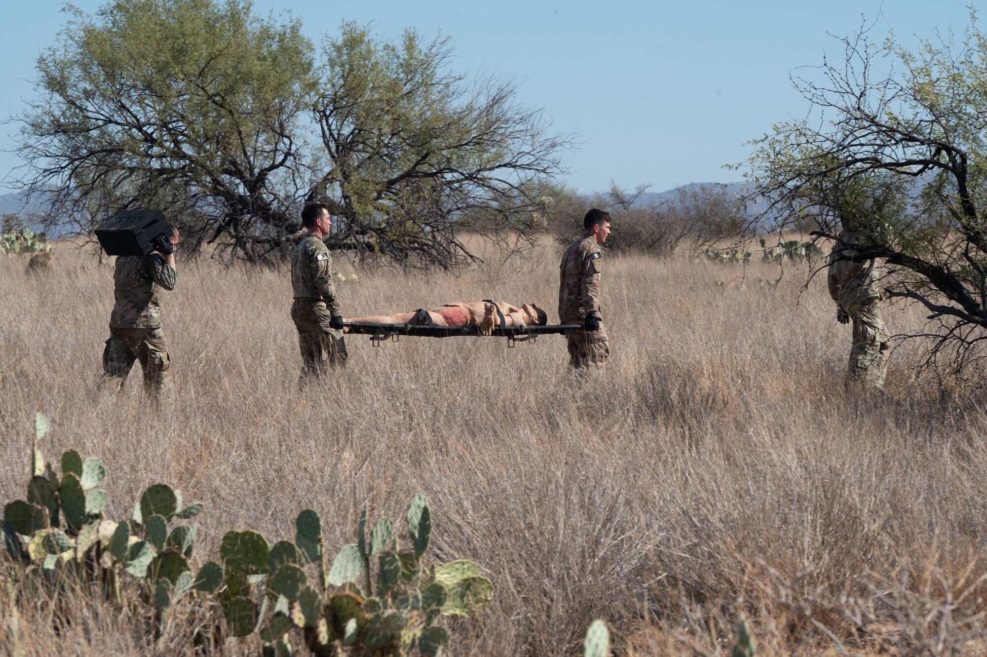 Candidates participating in a Combat Rescue Officer Phase II training exercise carry supplies through the desert at Davis-Monthan Air Force Base, Ariz., Oct. 18, 2023. A dummy was used for the candidates to simulate injury response techniques during the exercise. (U.S. Air Force photo by Airman 1st Class Robert Allen Cooke III)