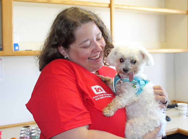 Lady in red USACE shirt holding therapy dog.